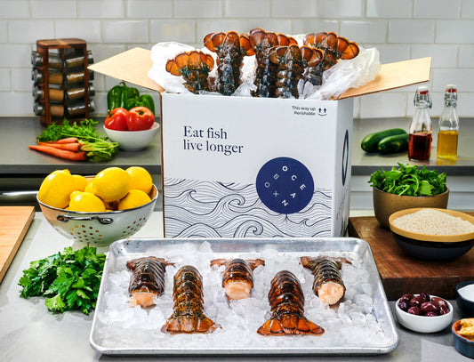 OceanBox Cold Water Lobster Tail Box with 10 lobster tails displayed on crushed ice alongside fresh lemons and herbs-Oceanbox