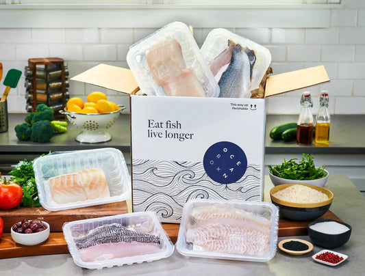 OceanBox White Fish Combo Box with black sea bass, branzino, cod, halibut and sole fillets surrounded by fresh kitchen ingredients-Oceanbox